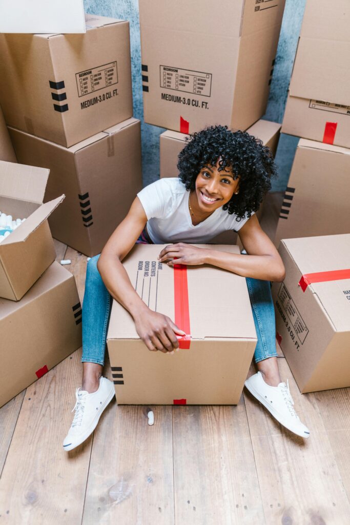 Happy woman sitting among boxes while packing for moving day. Perfect for relocation, moving, and lifestyle themes.